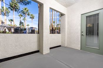 A white wall with a green door and a window with blinds.